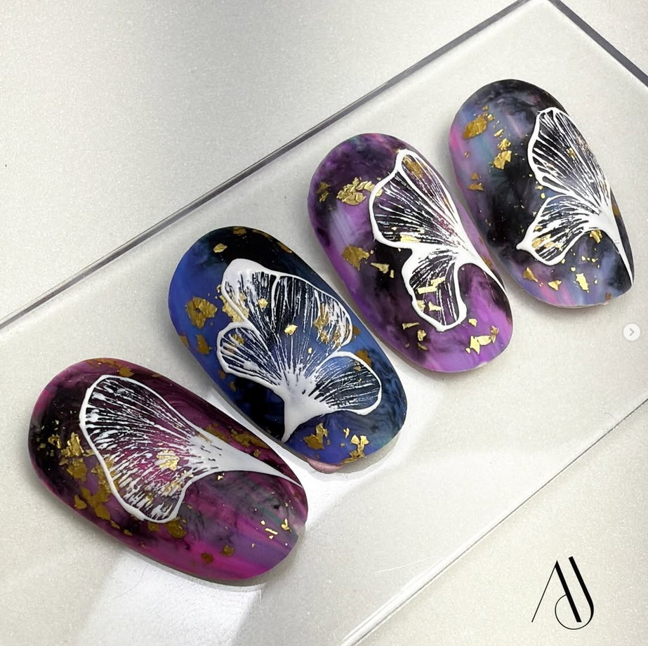 Nail art com folhas de ginkgo biloba e fundo marmorizado